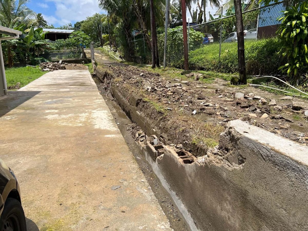 Before: the failed wall — broken blockwork, collapsed section and waterlogged ground along the boundary